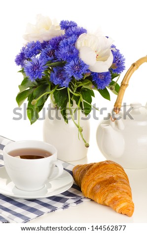 breakfast of tea and croissant on table with blue and white bouq