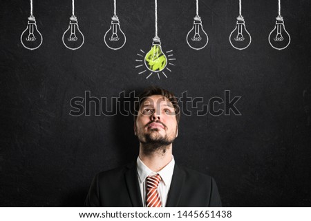 businessman having an idea symbolized by a lightbulb drawn on a blackboard
