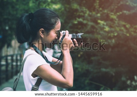 Beautiful Asian women with backpack aim camera in the jungle under warm light flare	