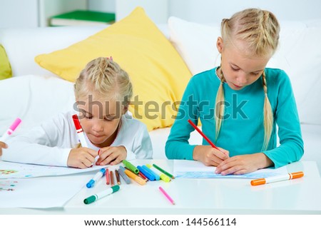 Portrait of lovely twins drawing with colorful pencils