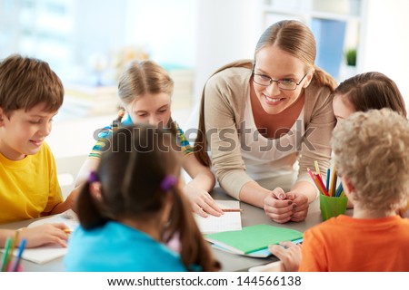 Portrait of diligent schoolkids and their teacher talking at lesson Royalty-Free Stock Photo #144566138