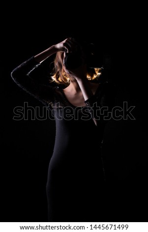 Asian Woman Photographer hold camera with external flash point to shoot subject, wear body suit. studio lighting black background isolated low key exposure, reporter journalist take photo celebrity