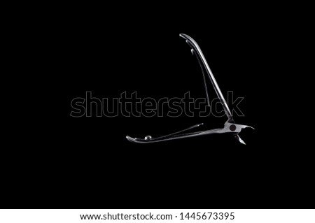 Massive forceps for manicure and pedicure on a black background, isolate