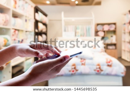 Woman use mobile phone, blur image of bed sales department in department stores as background.