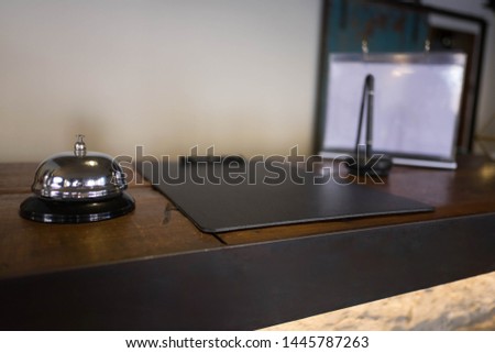 Service bell locating at reception. Silver call bell on table, receptionists on background.
