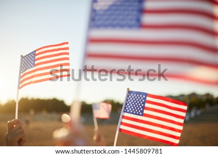 Group of unrecognizable people waving small American flags on sticks at parade outdoors