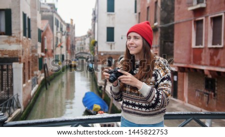 Young woman standing on the bridge and taking pictures of the surroundings.