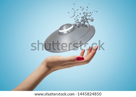 Closeup of woman's hand and little UFO above her palm, one side of UFO starting to break into little pieces, on light blue gradient background. Encounter UFOs. Experience mystery. 3d graphic design.