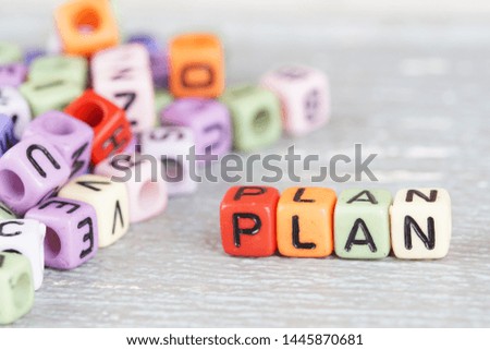 Selective focus. Wording "Plan" using coloured alphabet square beads on the wooden background