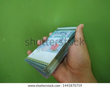 Stacking Ringgit Malaysia bank note on hand.