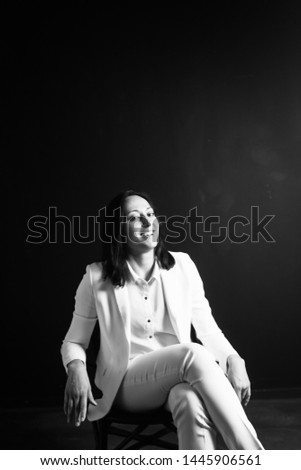 Studio portrait of an attractive young woman in a white suit against a plain black background