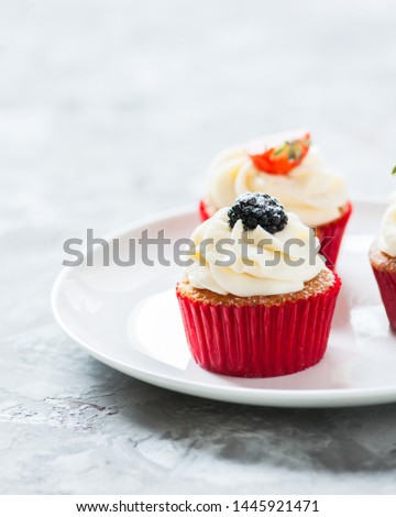 Three delicious cupcakes with berries in a plate. Close up.