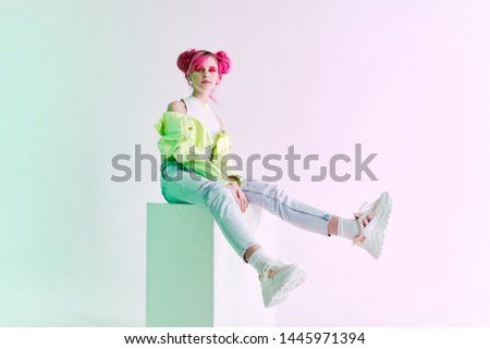 a woman with pink hair in stylish clothes sits on a cube fashion eighties nineties