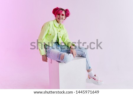 a woman with pink hair in stylish clothes sits on a cube fashion eighties nineties