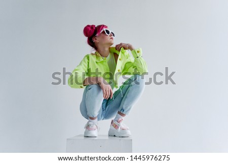 woman in glasses with pink hair sits on a cube