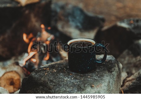Metal cup with fresh coffee near campfire. Breakfast at nature. Summer camp and hiking.