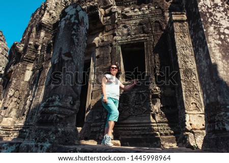 Adult woman tourist posing beside ancient Khmer ruins in Cambodia, Angkor Wat, Siem Reap