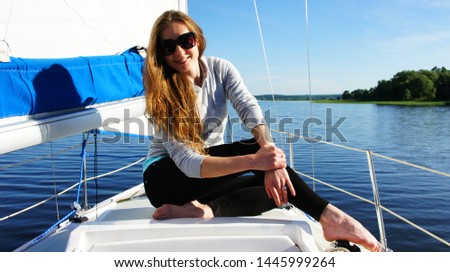 
Smiling girl sitting on the bow of a sailing boat during a trip over a large lake
