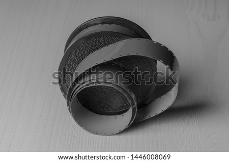Reel of vintage film on a light wooden background. Black and white, monochrome. 