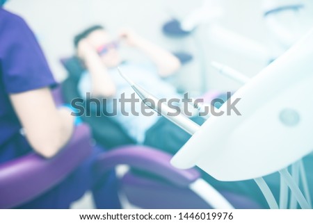 Blurred dental office. Tools are in the foreground. The boy with goggles in the dental chair