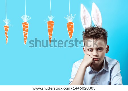 A bored boy in a light shirt and Bunny ears on a blue background
