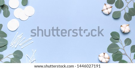 Cotton Cosmetic Makeup Removers Tampons. Spa concept. Flat lay background with cotton flowers, cotton pads, eared sticks, fresh eucalyptus twigs. Hygienic sanitary swabs on blue background Top view Royalty-Free Stock Photo #1446027191