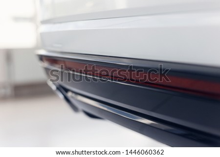 Close-up of reflector at the bottom of the bumper of a modern car standing in the showroom. The background is blurred