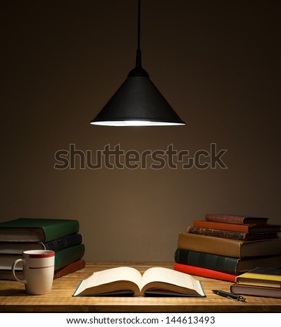 Books on wooden table under lamp light Royalty-Free Stock Photo #144613493