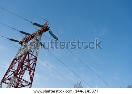 Close-up of a power line tower stands against a blue summer sky on a sunny day. The concept of electrification. Advertising space