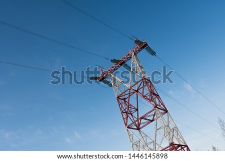 Side view of a power line tower standing against a blue summer sky on a sunny day. The concept of electrification. Copyspace