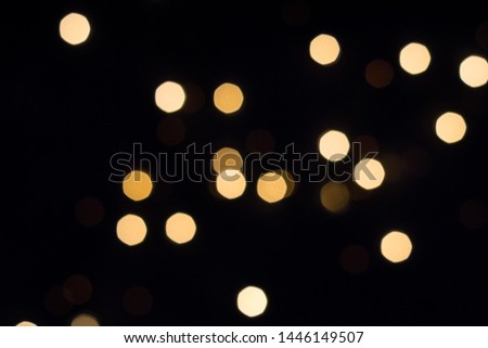 Golden bokeh lights glow on black. Holiday concept.