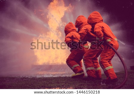 Firefighters, Firemen spraying high pressure water or suitable extinguishing agents to fire with copy space .