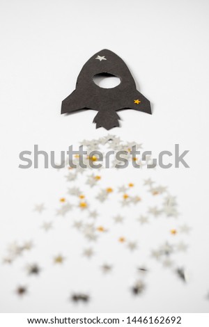 Paper cosmo rocket with glitter stars flat lay background