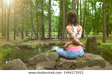 Beautiful young girl practicing yoga and meditation at sunrise in the forest. Shallow depth of field. Balance and spirituality concept