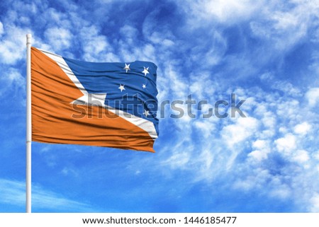 National flag of Tierra del Fluego Province Argentina on a flagpole in front of blue sky