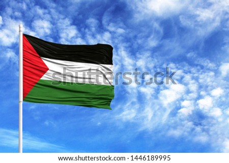 National flag of Palestine on a flagpole in front of blue sky
