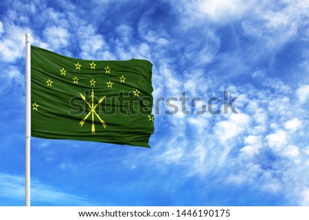 National flag of Adygea on a flagpole in front of blue sky
