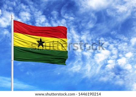 National flag of Ghana on a flagpole in front of blue sky