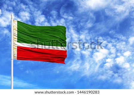 National flag of Chechen Republic on a flagpole in front of blue sky