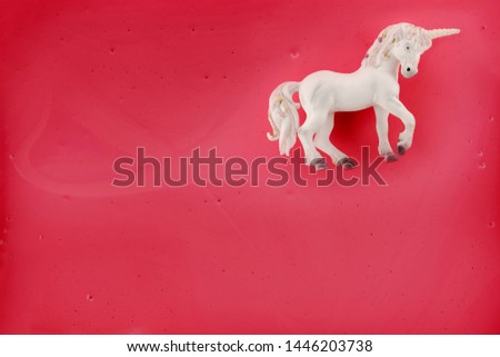 A white unicorn floats in front of a pink background.