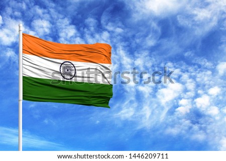 National flag of India on a flagpole in front of blue sky