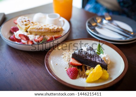 Picture of waffle pancake desert with vanilla ice cream, fresh strawberry and honey syrup and chocolate brownies