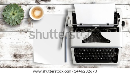 overhead shot of typewriter and paper on white wooden table