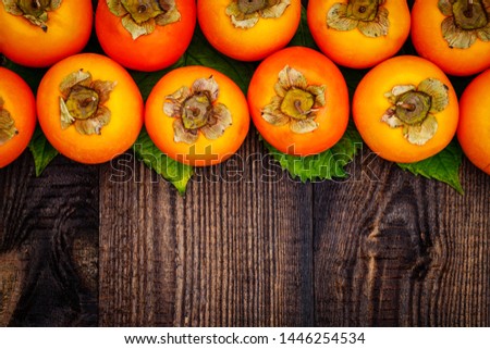 Ripe orange persimmon fruit on brown wooden table. Persimmons background with copy space, text place