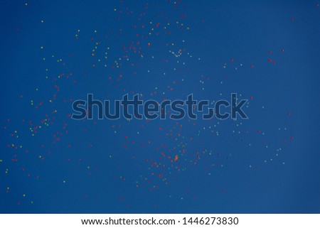 Many bright balloons fly in the air against the blue sky. Festive mood.