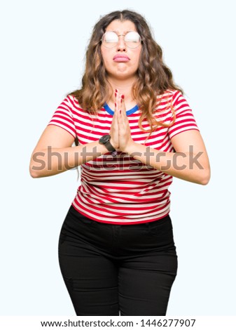 Young beautiful woman wearing glasses begging and praying with hands together with hope expression on face very emotional and worried. Asking for forgiveness. Religion concept.