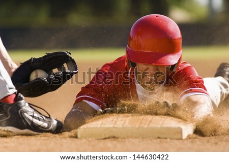 Closeup of a baseball player sliding to the base Royalty-Free Stock Photo #144630422