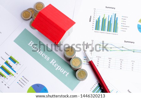 Red house and money coins and pen on business report paper backgrounds above, Top views