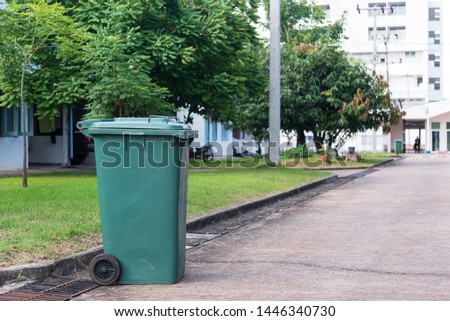 Green garbage bin in front of the house.Public trash on the side of the road.Infectious control concept. Royalty-Free Stock Photo #1446340730