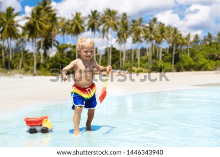 Child playing on tropical beach with palm trees. Little baby boy at sea shore. Family summer vacation. Kids play with water and sand toys. Ocean and island fun. Travel with young children in Asia.